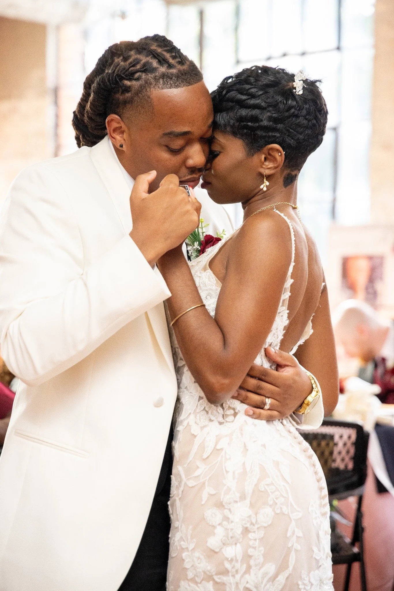 A couple in wedding attire sharing an intimate moment at their wedding reception.