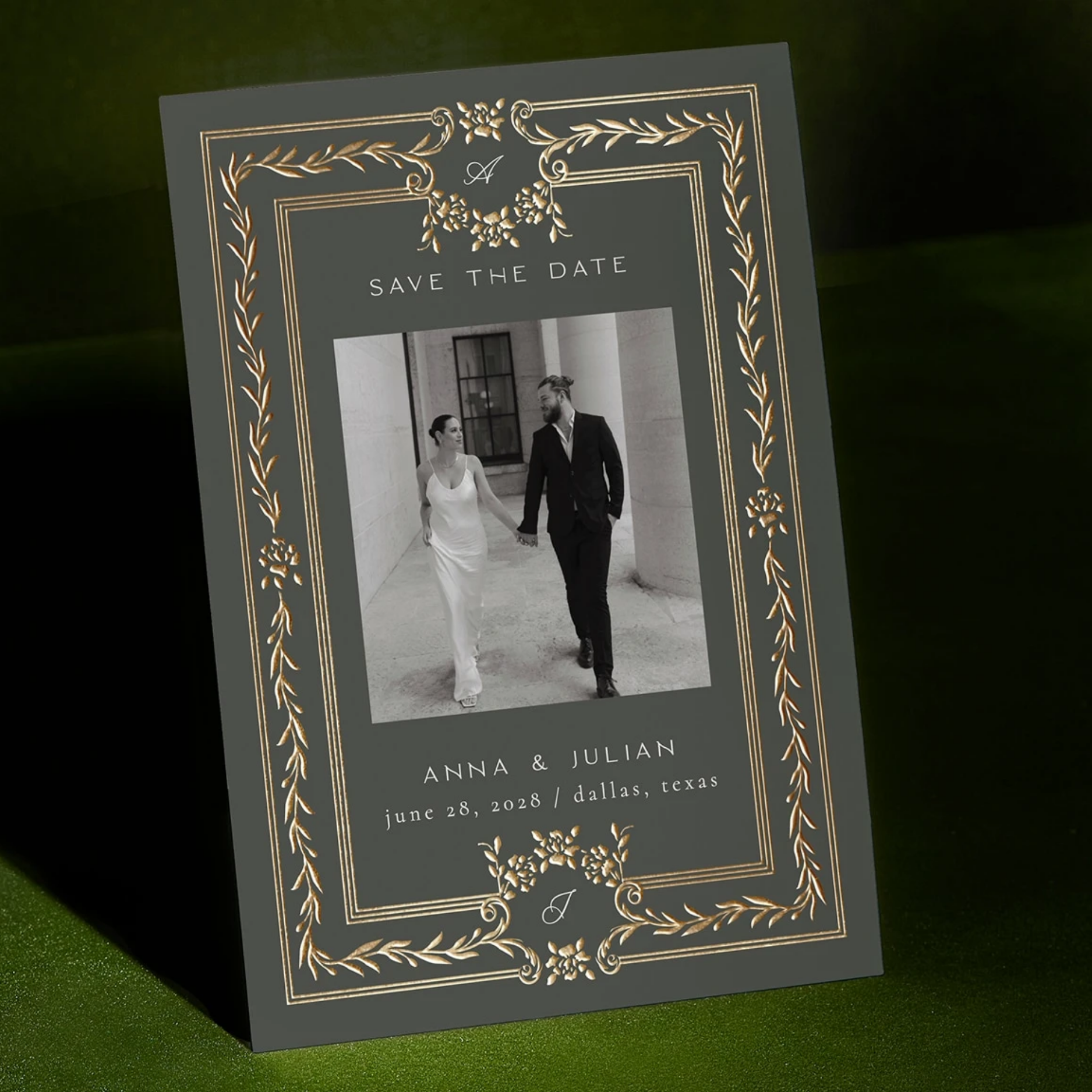 Save the date wedding invitation featuring a black and white photo of a bride and groom holding hands, with decorative gold floral borders, text indicating the names Anna and Julian, wedding date June 28, 2028, in Dallas, Texas.