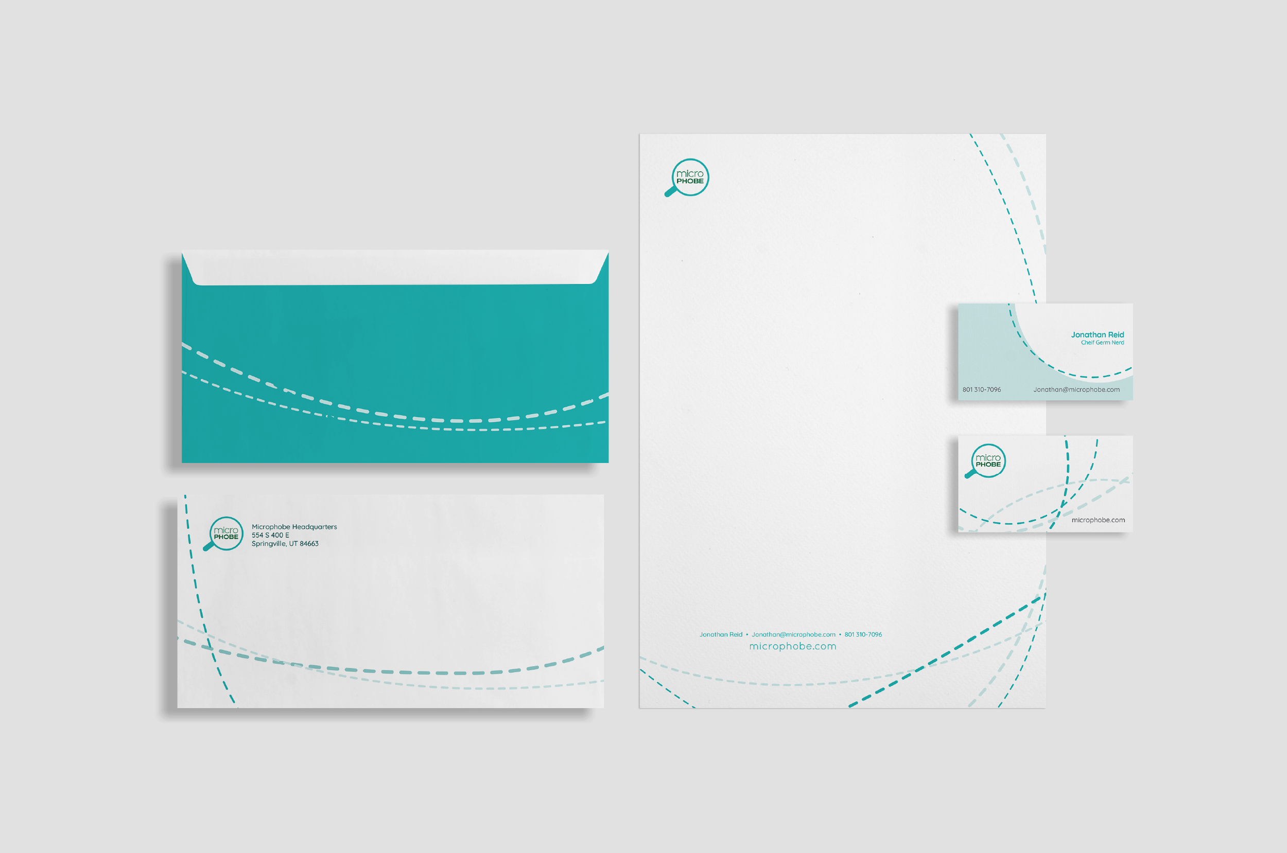 Set of corporate stationery including envelopes, letterhead, business cards, all with a white and teal color scheme and a dotted line design, featuring the MicroPhobe logo and contact information.
