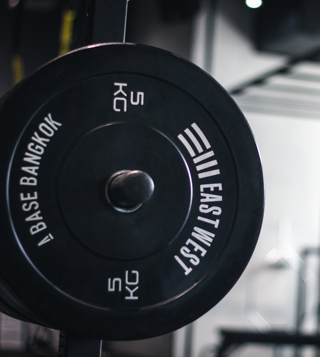 A black weight plate with weights labeled in kilograms, from 5KG up to 25KG, mounted on a barbell in a gym.