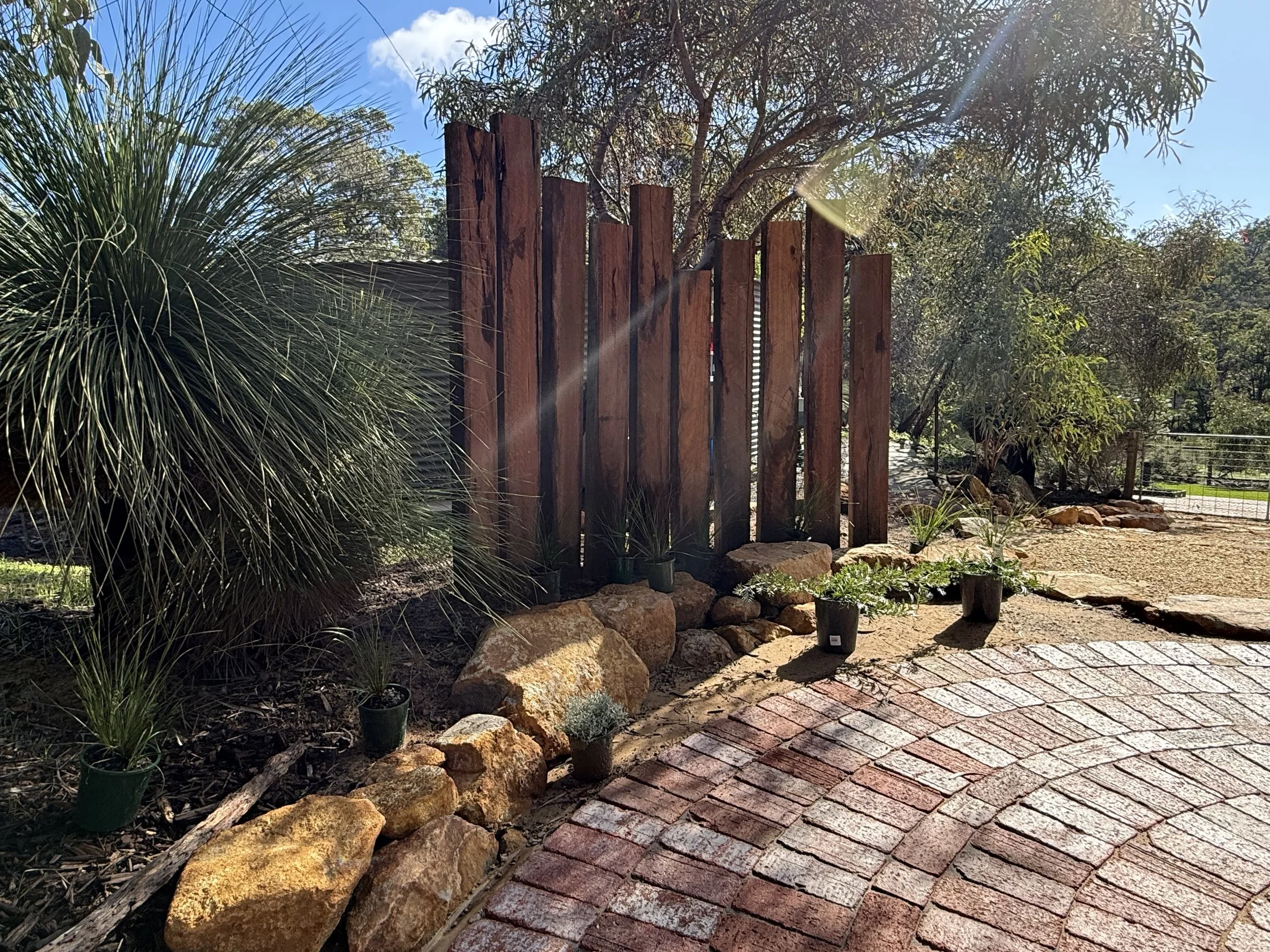 Jarrah posts screen a water tank and match seamlessly with the recycled brick path and fully grown grass tree