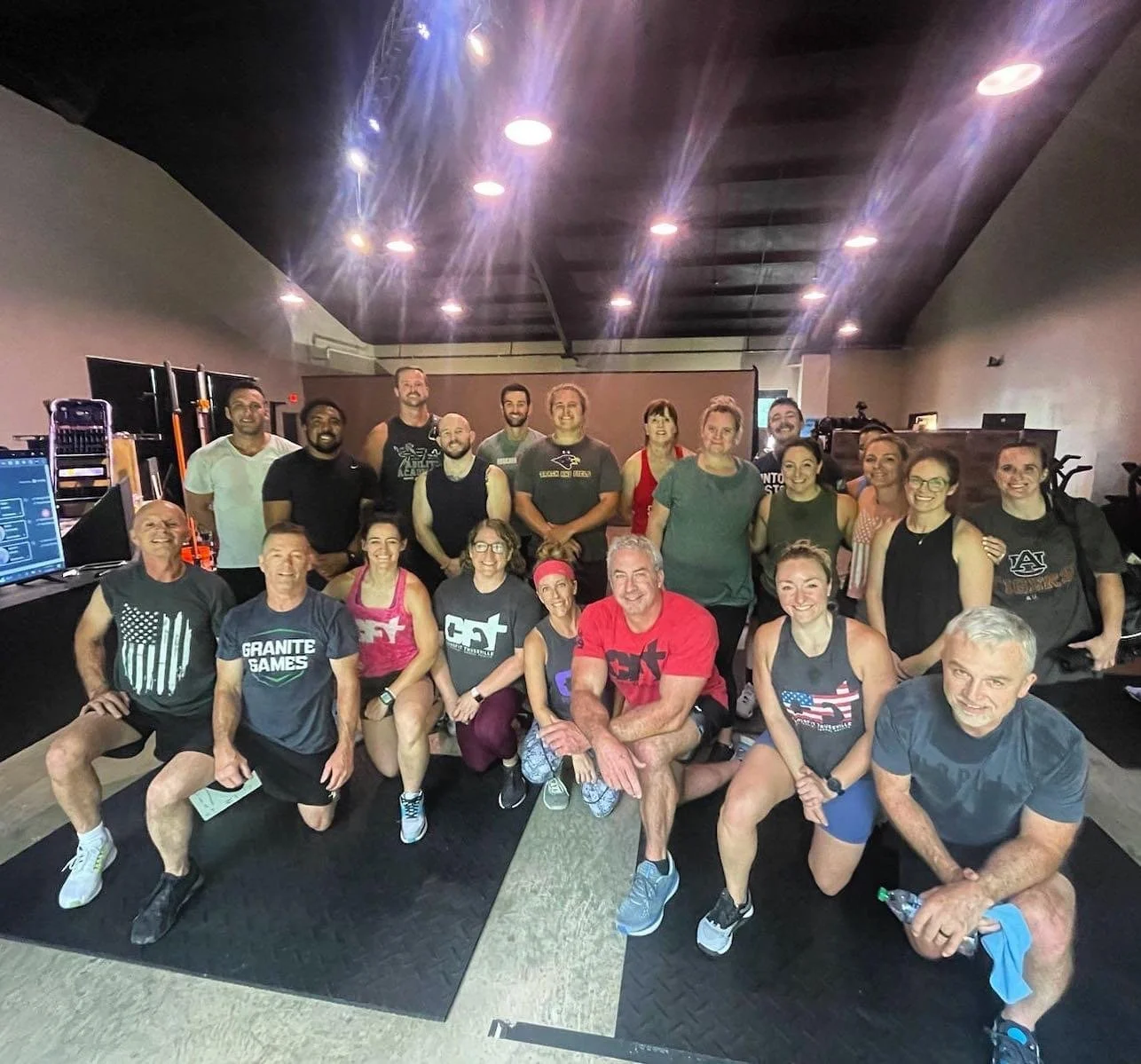 Group of men and women in a gym, posing for a photo after a workout class.
