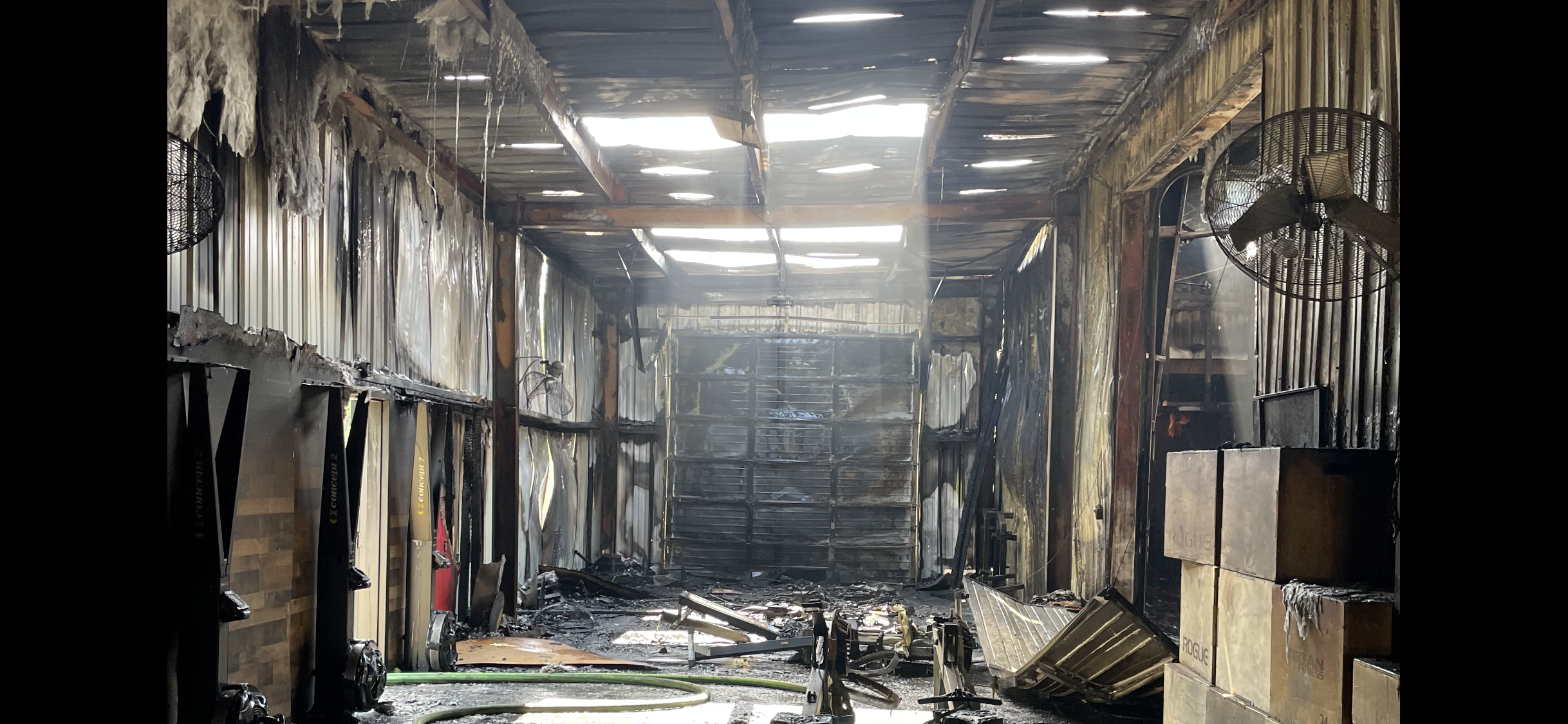Subjected to fire damage, this is an interior of a building with burnt walls, ceiling, and debris on the floor. Some walls and fixtures show signs of charring and smoke damage.