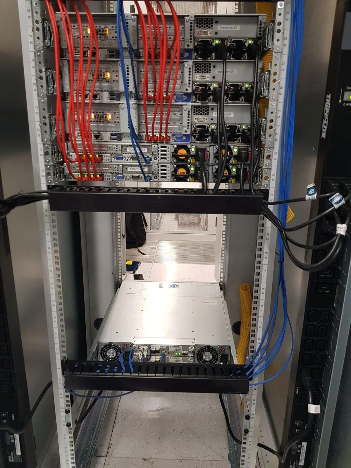 Data centre server rack with installed hardware, power supplies, and network cabling following rack and stack installation