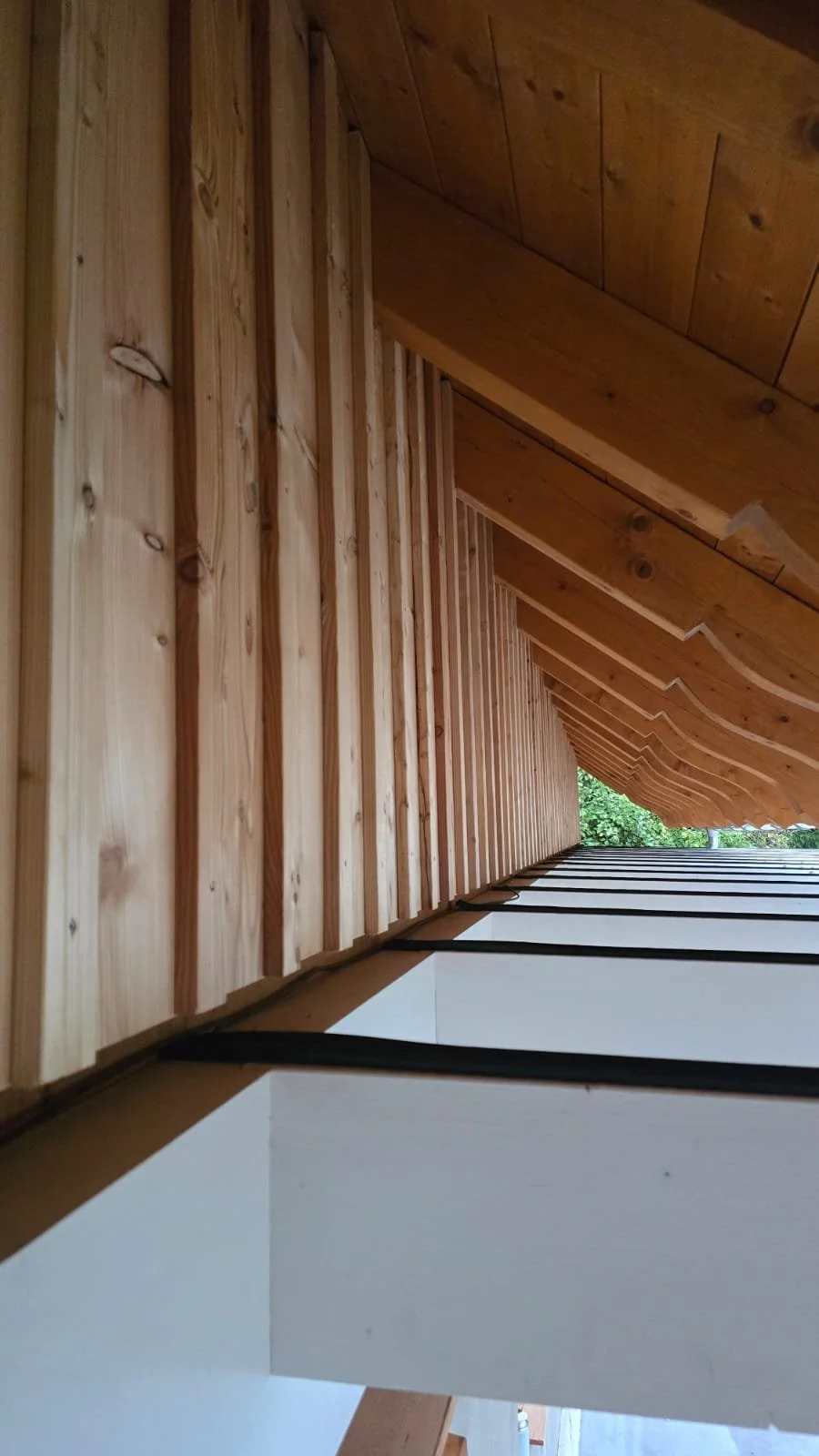 View of a wooden staircase with railings, showing natural wood finish and an outdoor view at the bottom.