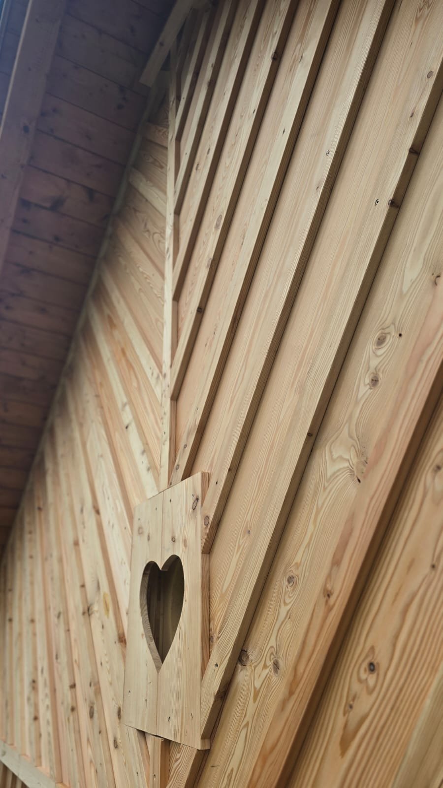 Wood-paneled interior wall with a wooden cutout of a heart shape.