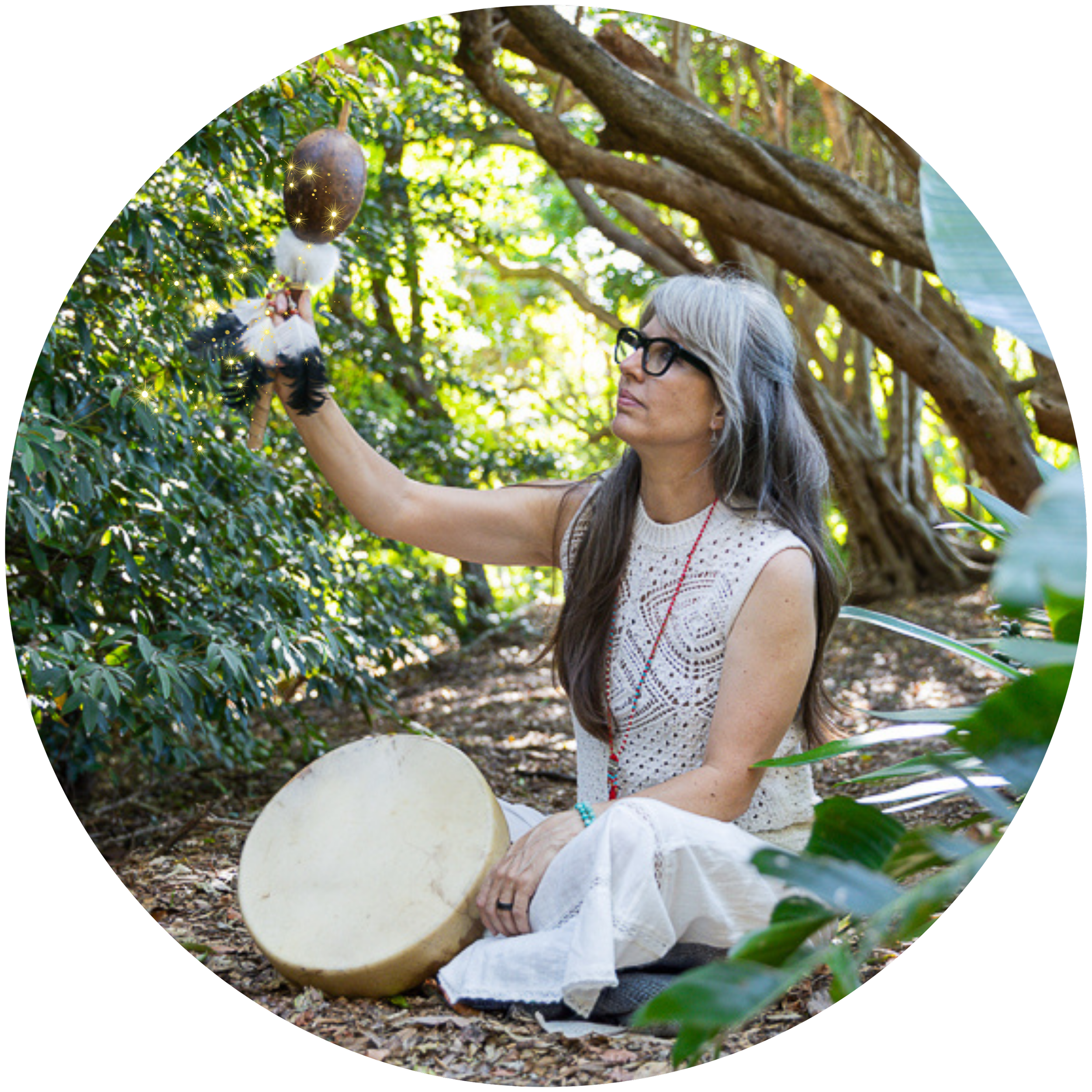 Alrina Laker, Lineage Carrier of the Munay-Ki Rites, seated in a forest with shamanic drum and rattle representing her transmission of the ancient Andean Q'ero tradition