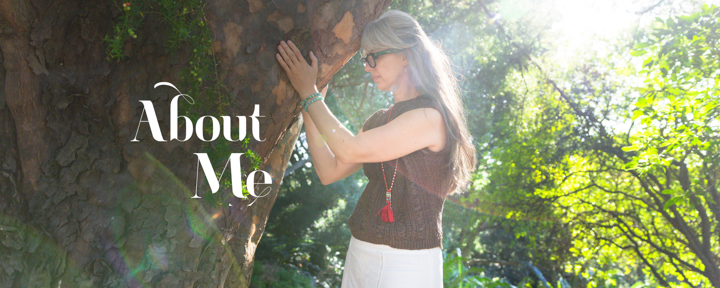 Alrina Laker, Master Practitioner of Shamanic Energy Medicine, with hands resting on a tree in dappled sunlight