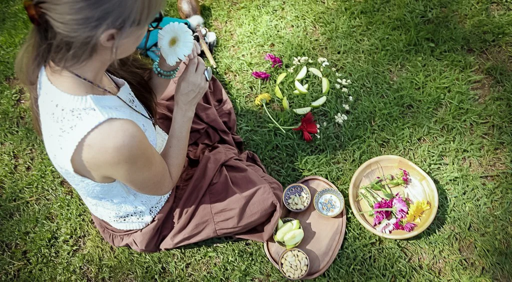 Alrina Laker seated on grass during a shamanic healing ceremony with flowers and sacred offerings