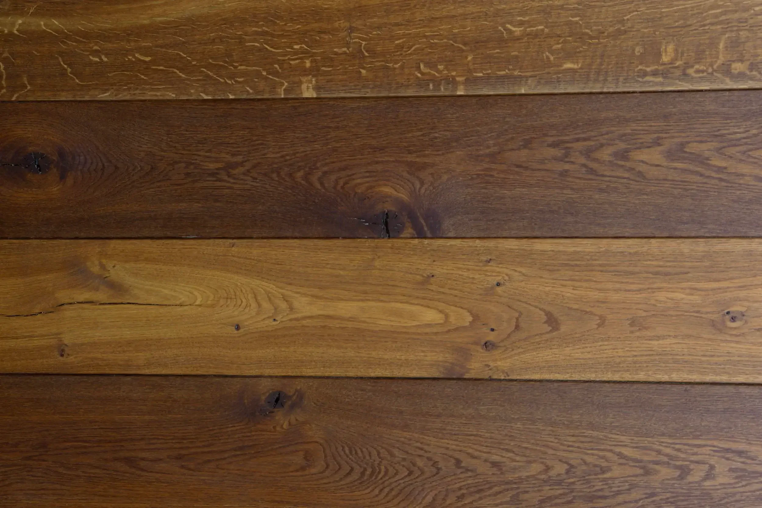 Planches de bois massif en différentes nuances de brun, vue de haut.