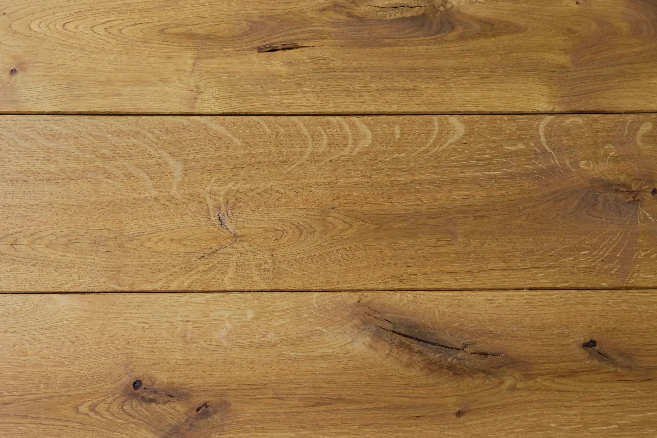 Trois planches de bois clair avec des nœuds et des veinures visibles.