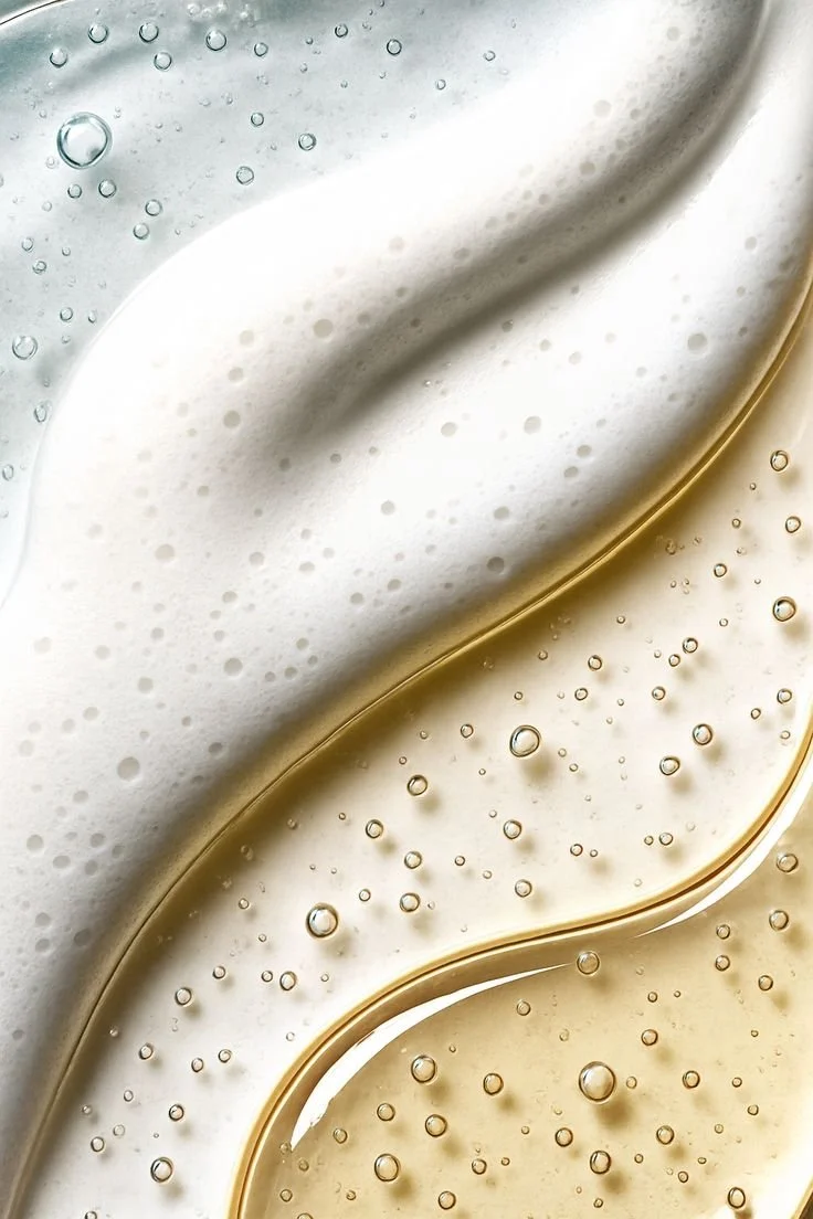 Close-up of two differently colored liquids, one white and one beige, with bubbles and smooth, flowing textures.