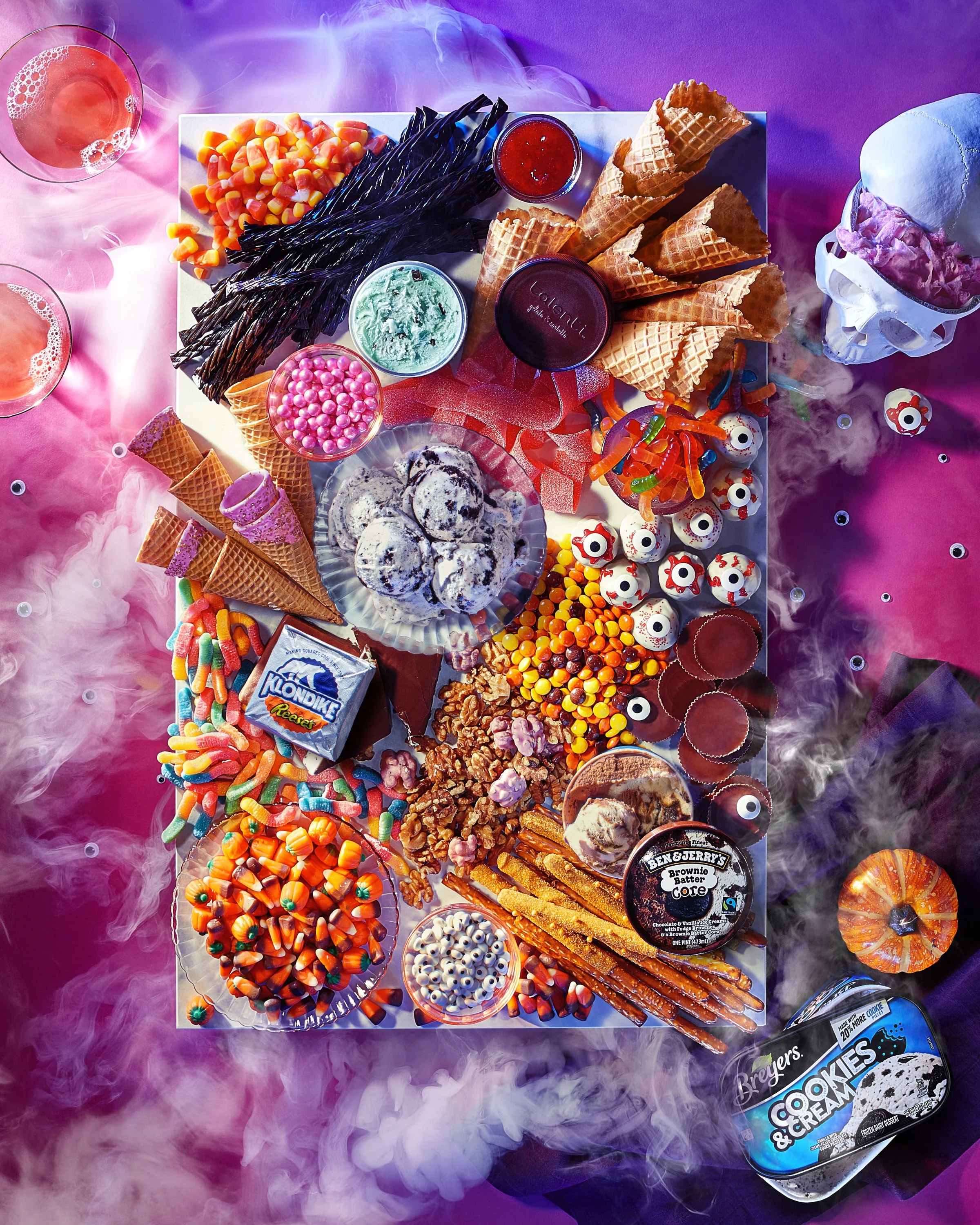 A colorful Halloween-themed candy and dessert platter with various candies, ice cream, and snacks, surrounded by pink and purple smoke for a spooky effect. Chicago Milwaukee Midwest Illinois Food Food beverage Food Drink Savory Photographers photogra