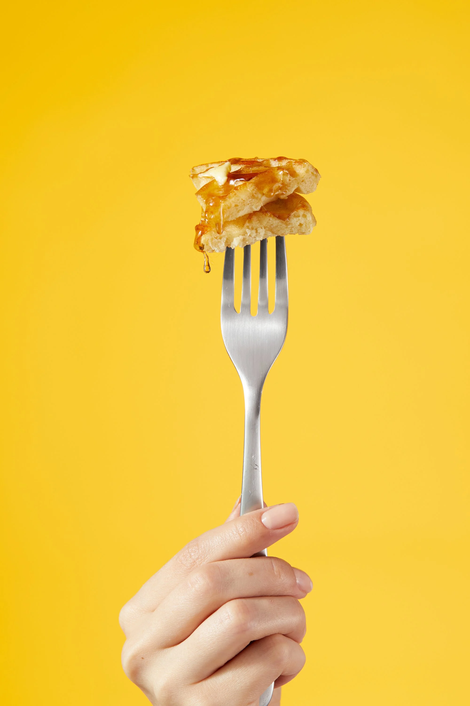 A hand holding a fork with a slice of apple pie with caramel sauce against a yellow background. Chicago Milwaukee Midwest Illinois Food Food beverage Food Drink Savory Photographers photographer photography videography videographer CPG Bennett Fuhrma