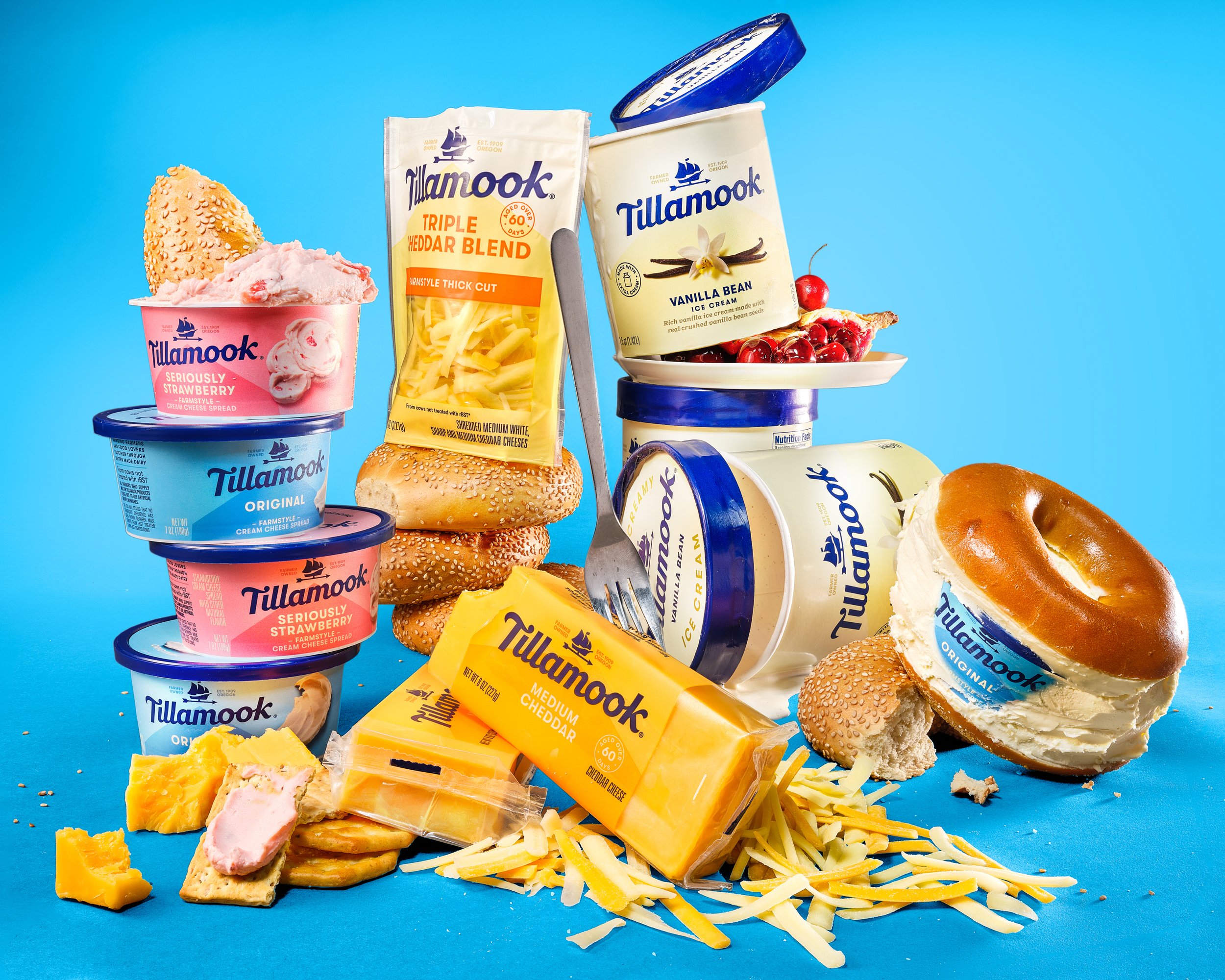 Assortment of Tillamook dairy products including cheese, ice cream, and yogurt, along with bagels, cookies, and toppings on a bright blue background. Chicago Milwaukee Midwest Illinois Food Food beverage Food Drink Savory Photographers photographer p