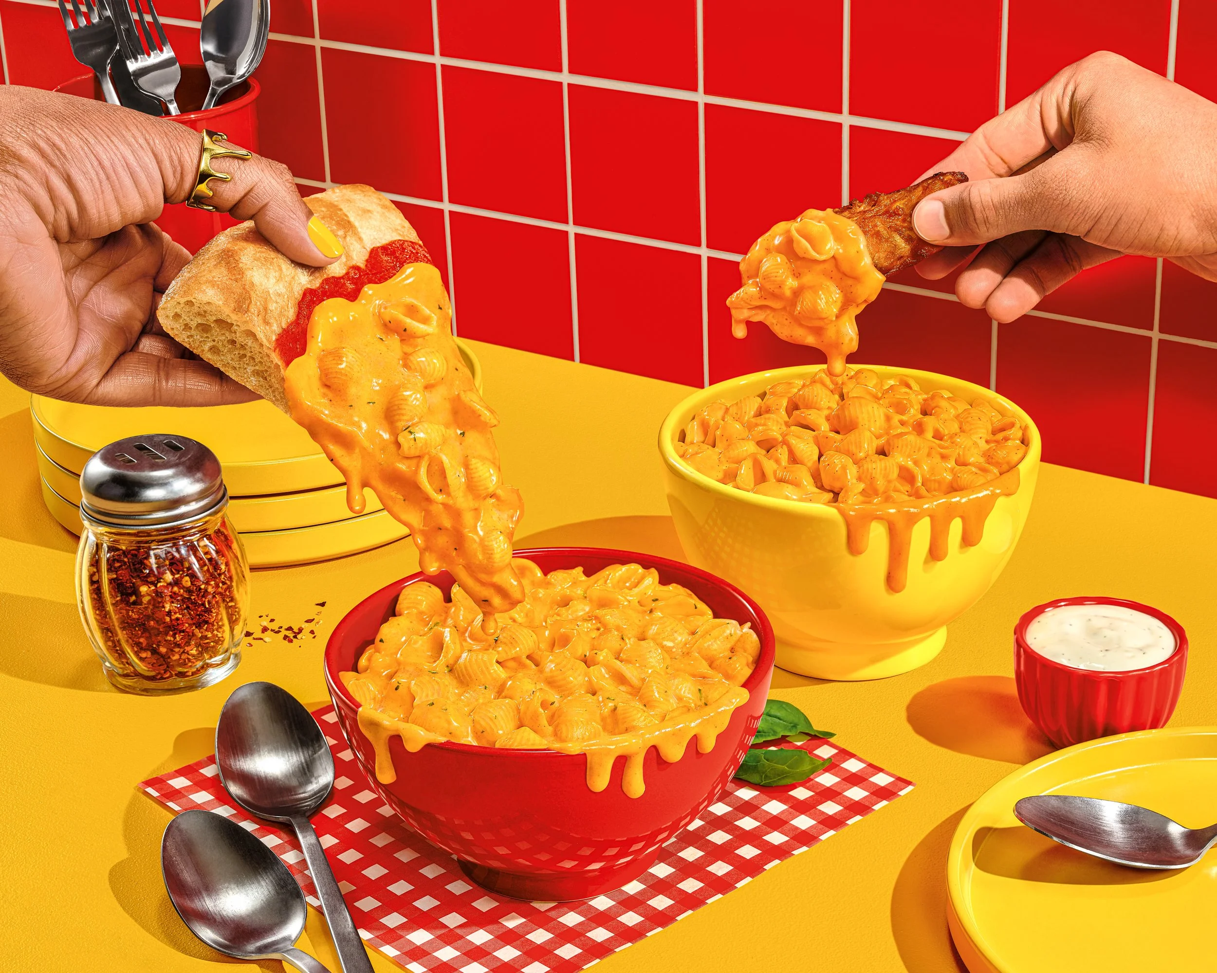 Two people dipping breadsticks into bowls of macaroni and cheese in a colorful kitchen with red tiled wall and yellow countertop. Chicago Milwaukee Midwest Illinois Food Food beverage Food Drink Savory Photographers photographer photography videograp