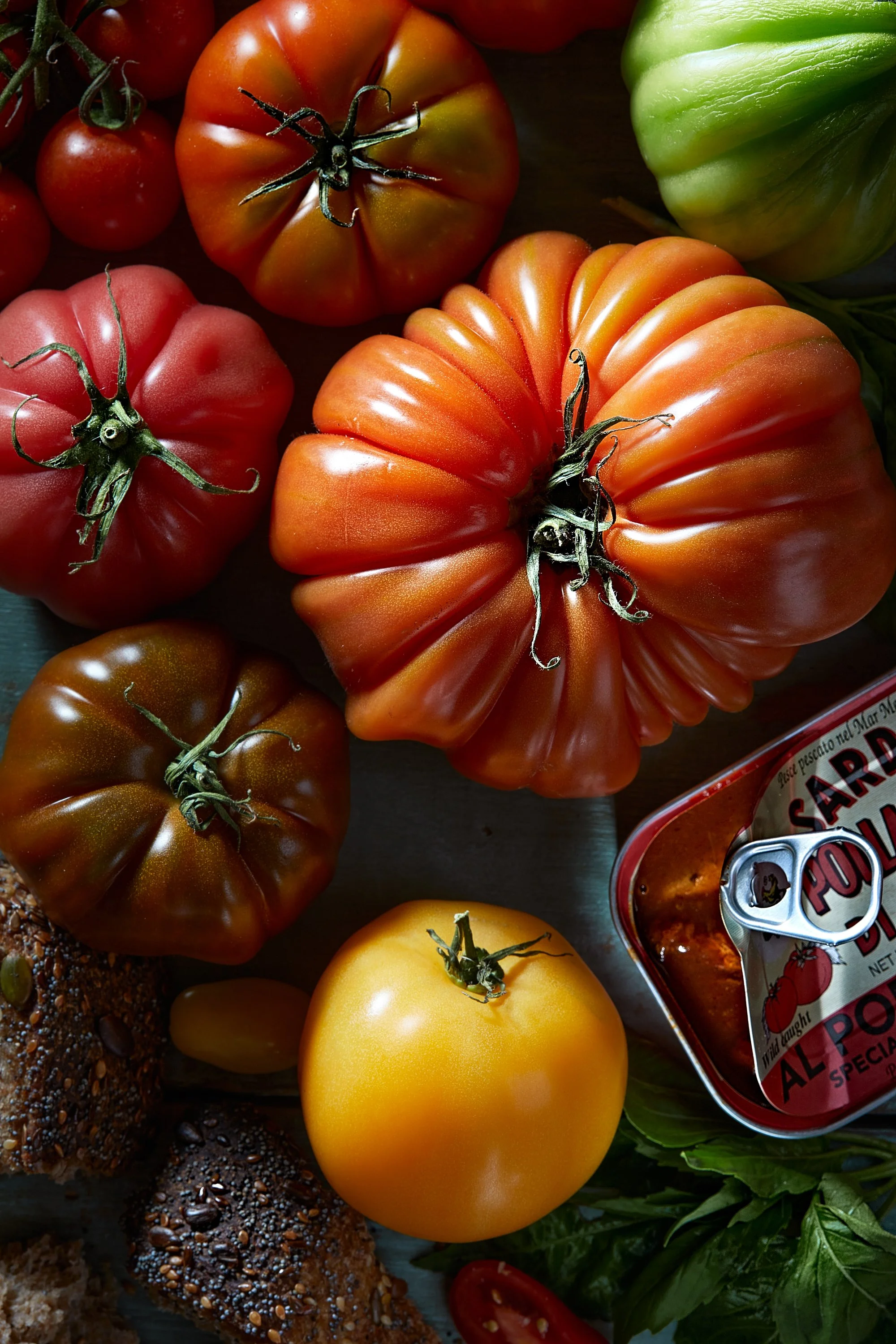 Assorted heirloom tomatoes, a tin of tomato sauce, and fresh herbs on a wooden surface. Chicago Milwaukee Midwest Illinois Food Food beverage Food Drink Savory Photographers photographer photography videography videographer CPG Bennett Fuhrman Ben Ti