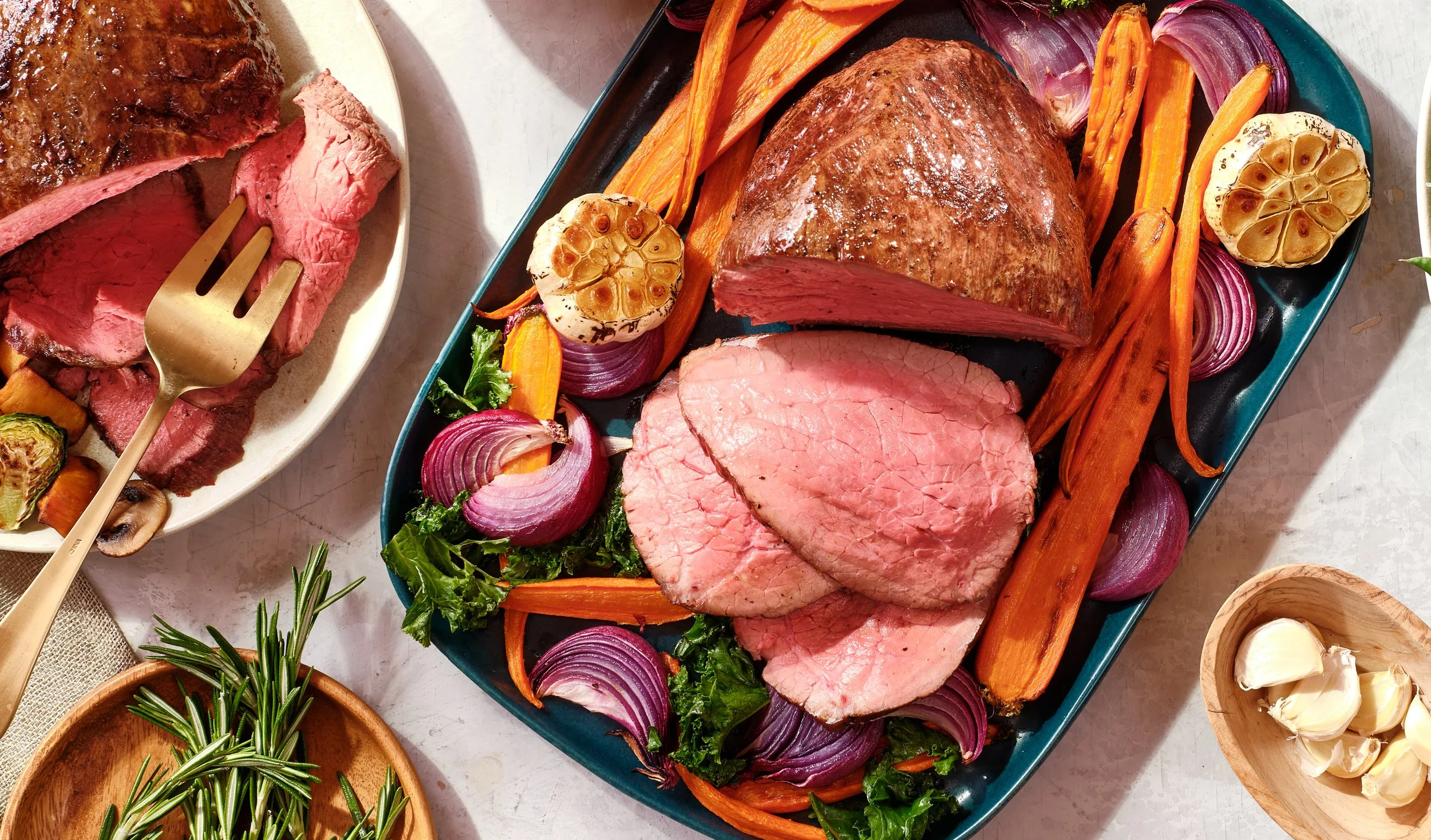 A platter with cooked beef, sliced and surrounded by roasted garlic, carrots, red onions, and leafy greens. Chicago Milwaukee Midwest Illinois Food Food beverage Food Drink Savory Photographers photographer photography videography videographer CPG Be