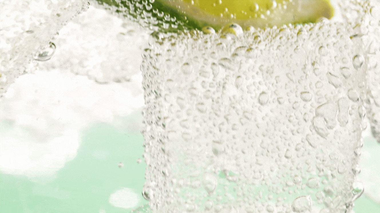 Close-up of a glass with a lime wedge, filled with a carbonated beverage, with bubbles visible on the surface. Chicago Milwaukee Midwest Illinois Food Food beverage Food Drink Savory Photographers photographer photography videography videographer CPG