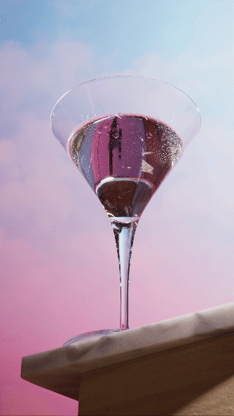 A martini glass with pink liquid on a table against a pastel sky background. Chicago Milwaukee Midwest Illinois Food Food beverage Food Drink Savory Photographers photographer photography videography videographer CPG Bennett Fuhrman Ben Tiny Scheme
