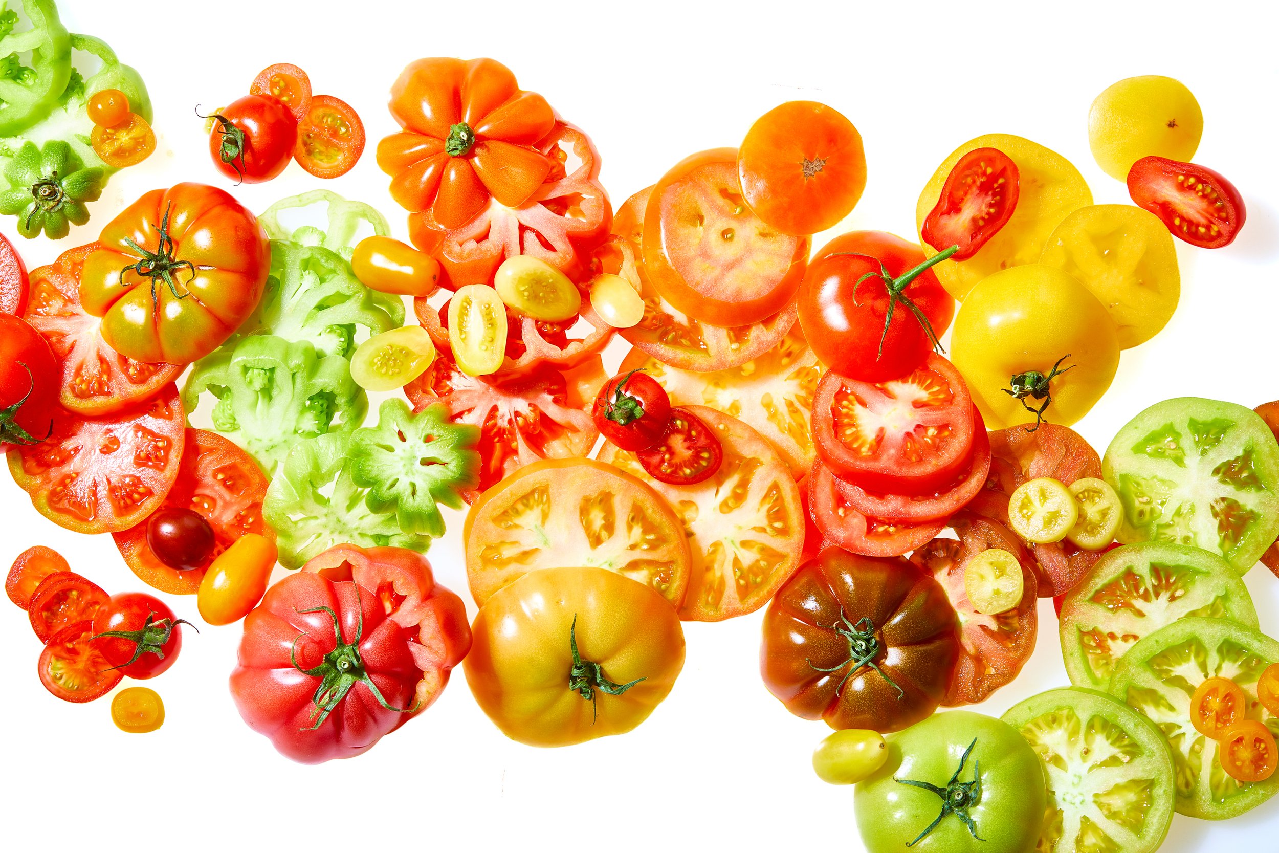 Colorful assortment of sliced cherry, heirloom, and other tomatoes on a white background. Chicago Milwaukee Midwest Illinois Food Food beverage Food Drink Savory Photographers photographer photography videography videographer CPG Bennett Fuhrman Ben 