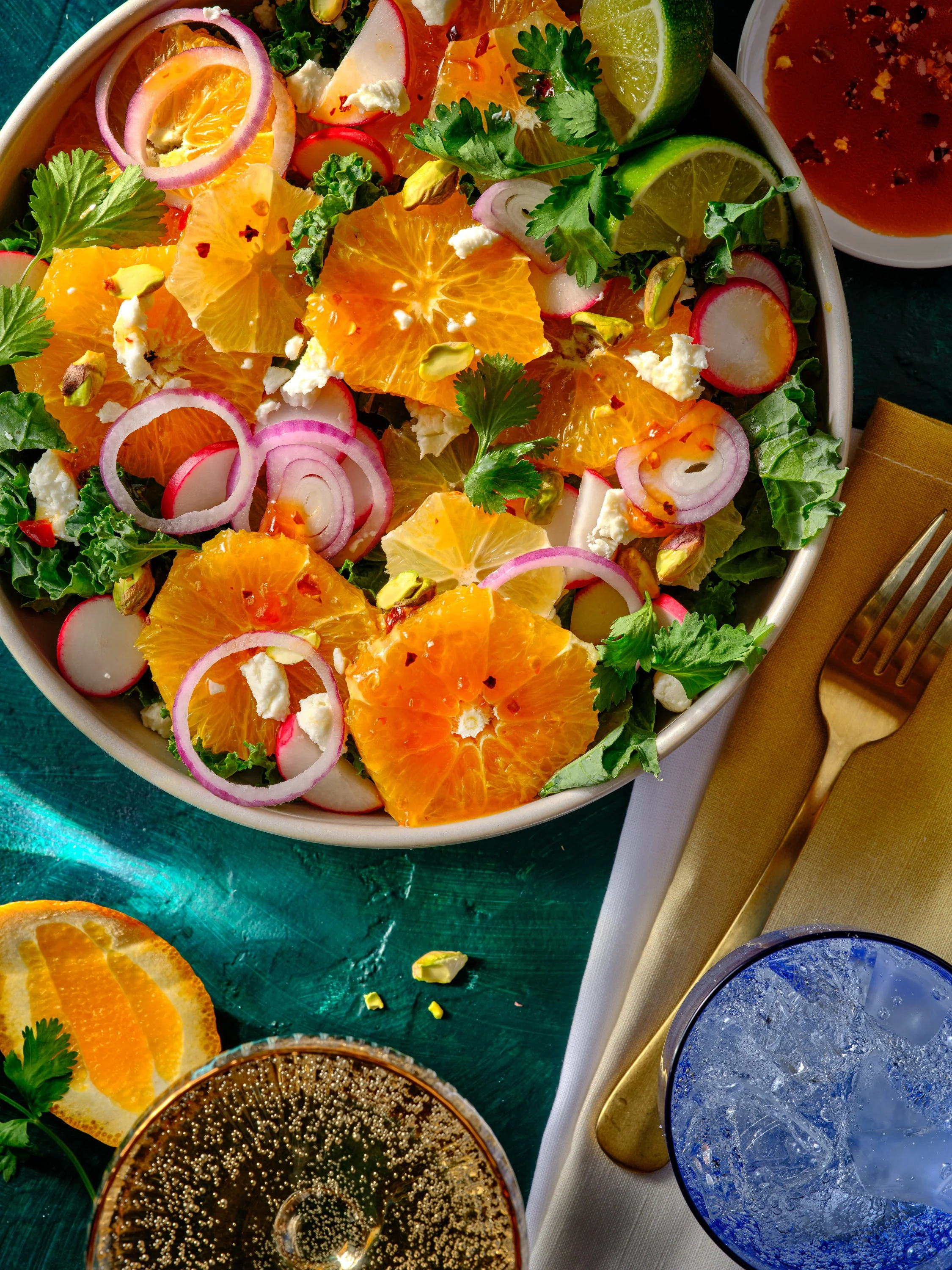 A fresh citrus salad with orange slices, radish slices, red onion, cilantro, and crumbled cheese in a bowl. Accompanying drinks and garnishes are also visible. Chicago Milwaukee Midwest Illinois Food Food beverage Food Drink Savory Photographers phot