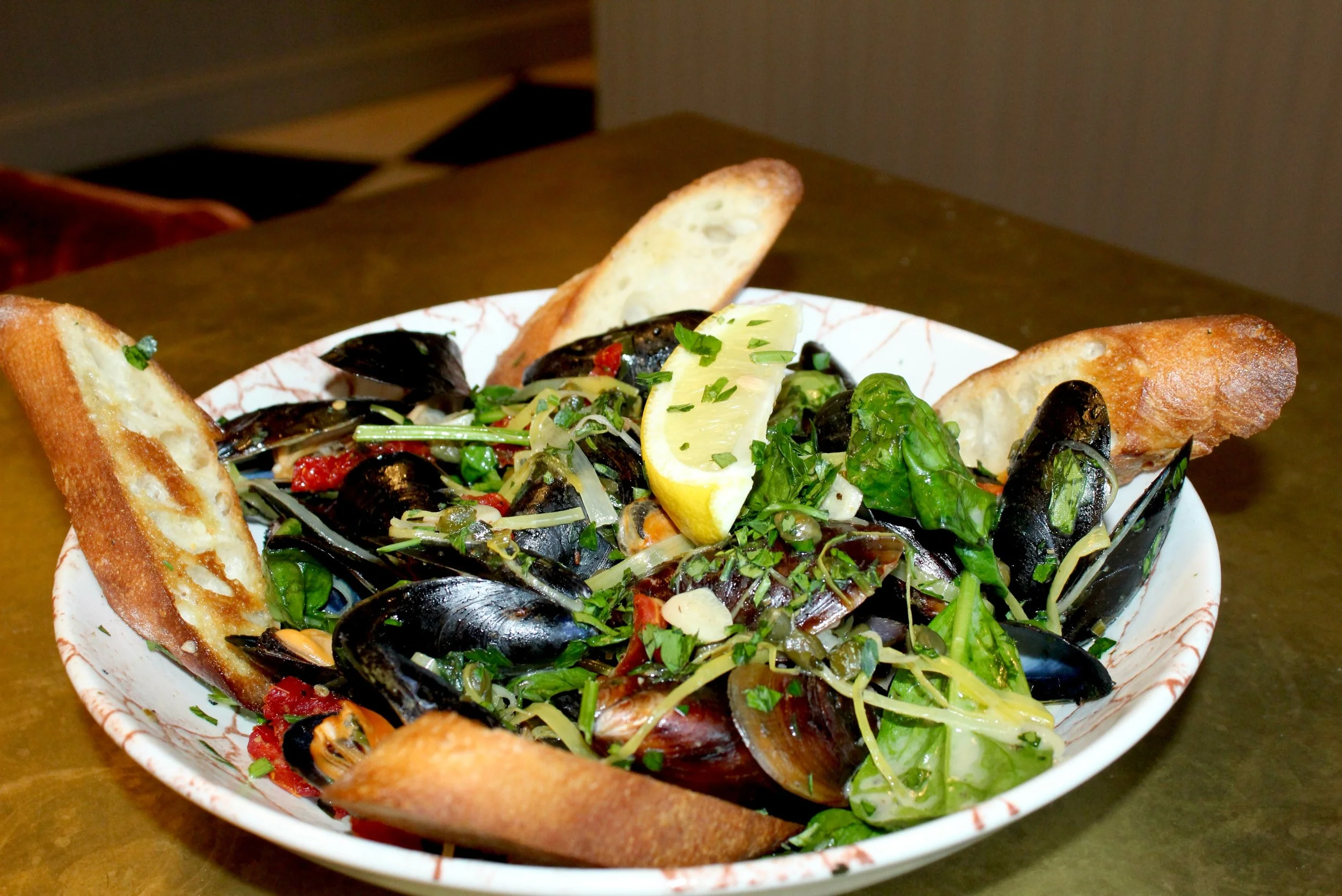 Every last bite and every last sip 

Fresh mussels in a white wine lemon broth with spinach, tomatoes, capers, leeks, garlic, and parsley &mdash; served with crostinis because leaving the broth behind simply isn&rsquo;t an option.