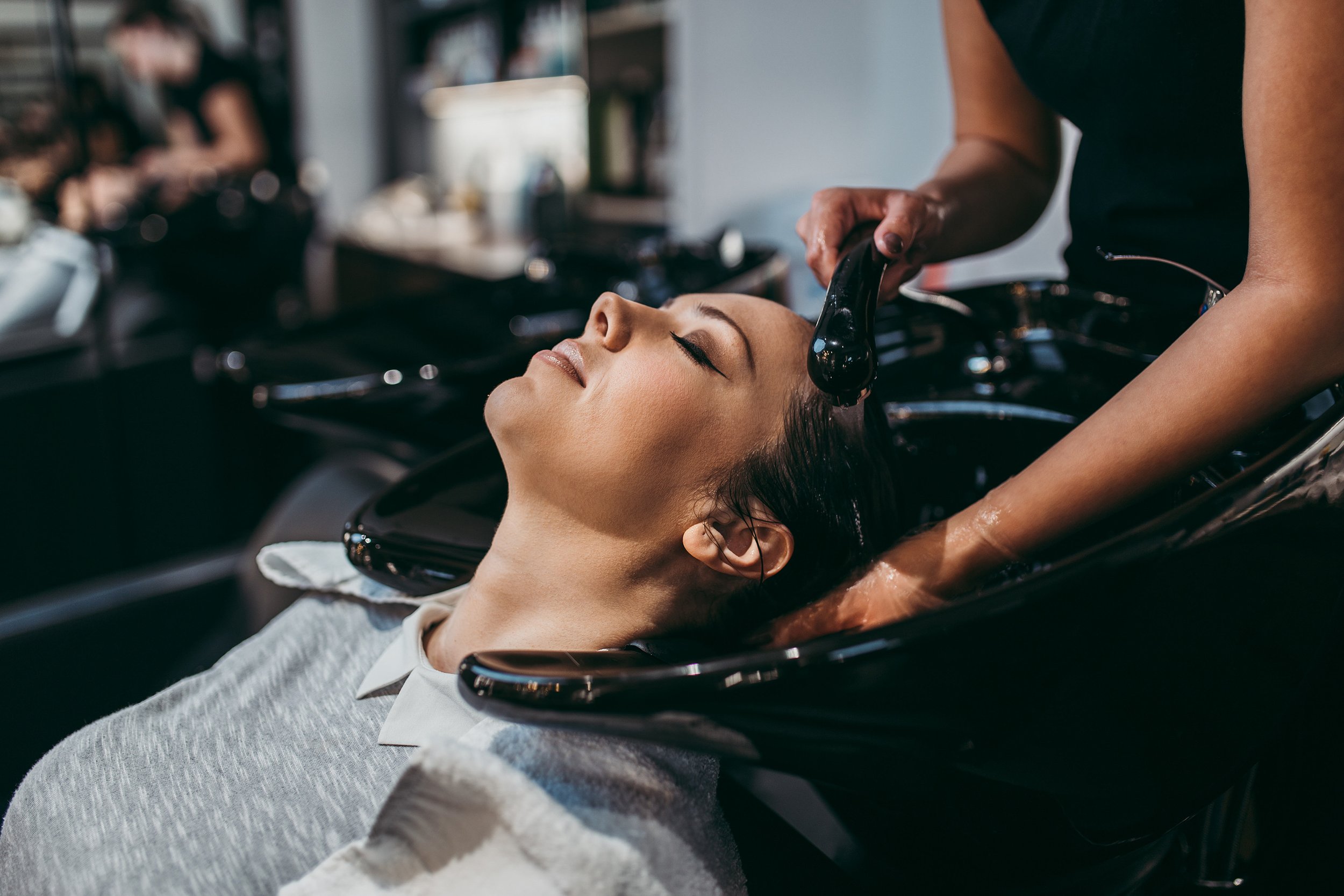 Client relaxing as hairstylist provides a luxurious hair wash in a private salon suite, highlighting professional care by independent beauty professionals.