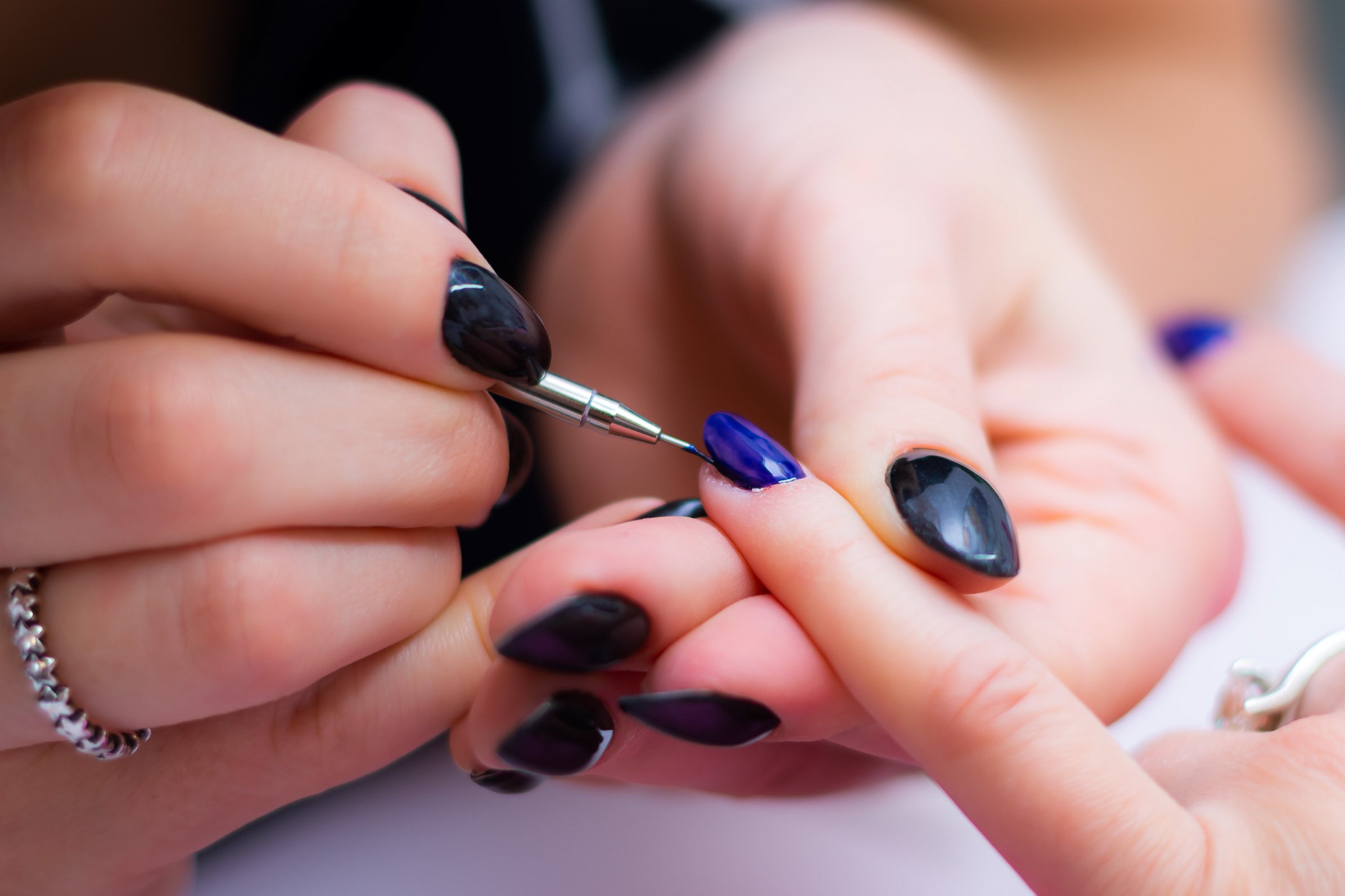 Manicurist applying deep blue polish to a client’s nails in a luxury salon suite, showcasing professional nail care by independent beauty professionals.