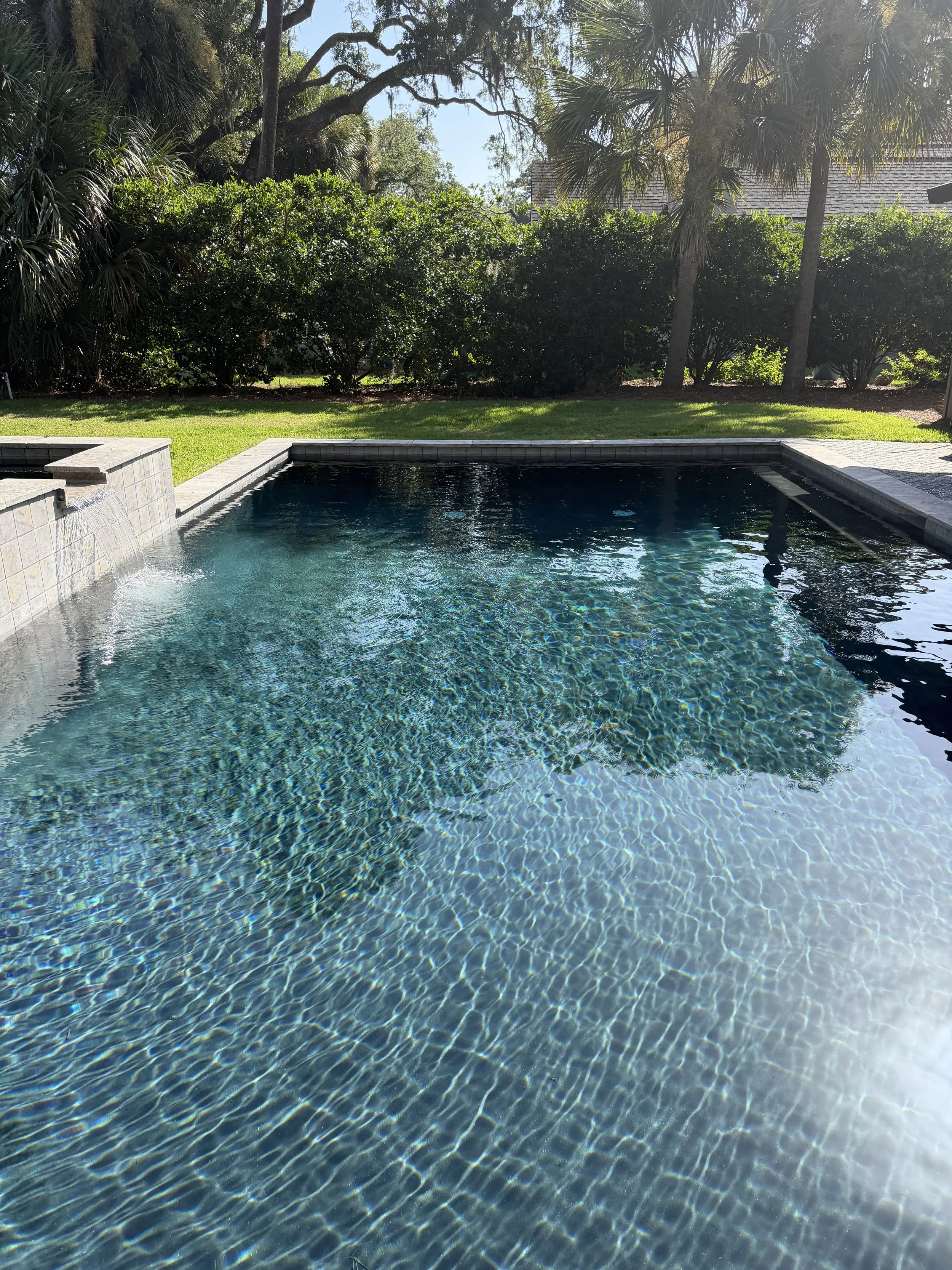 Close-up of a metal pool ladder with a blue swimming pool in the background, taken outdoor on a sunny day.