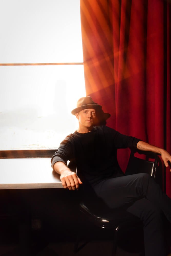 Jason Mraz sitting in front of a window