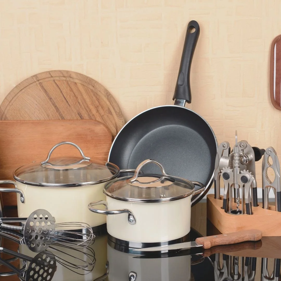 Kitchen countertop with pots, a frying pan, baking utensils, and chopping boards.