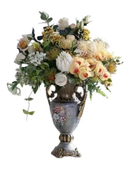 An ornate vase filled with a variety of white, cream, and yellow flowers, and greenery.