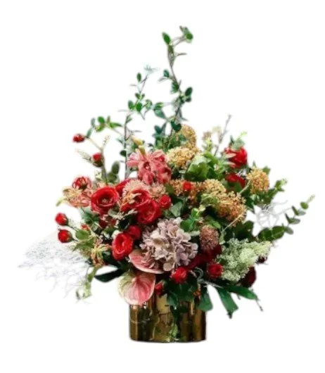 A vibrant floral arrangement in a gold vase with pink roses, purple flowers, greenery, and dried elements.