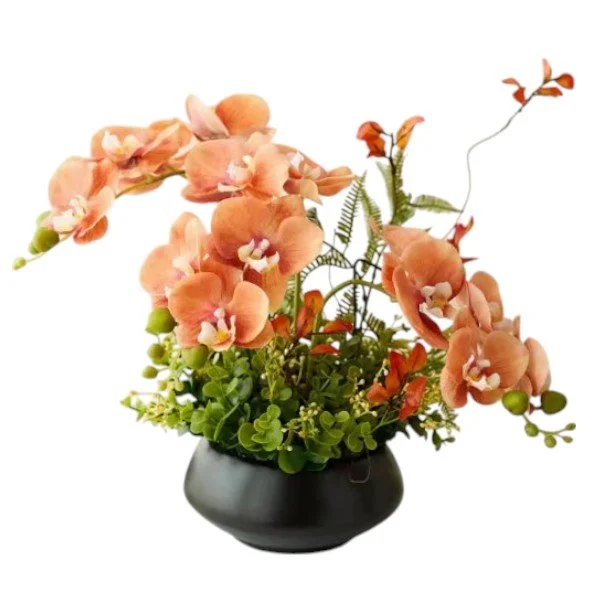 Arrangement of peach-colored orchids with green foliage in a black vase