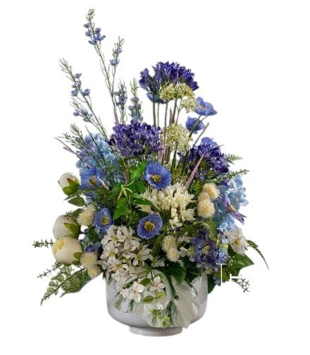 White and blue floral arrangement in a glass vase, including lavender, daisies, and other mixed flowers.