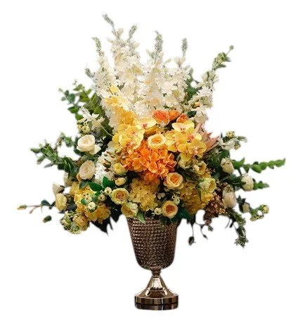 Arrangement of white, yellow, and orange flowers in a decorative metallic vase.