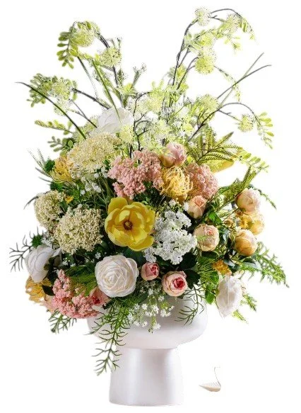 A floral arrangement featuring white, pink, and yellow flowers in a white vase.