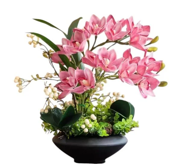 Pink and white artificial flowers in a black vase with green leaves and small white berries.
