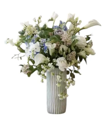 White and light purple flower bouquet in a tall, striped gray vase.