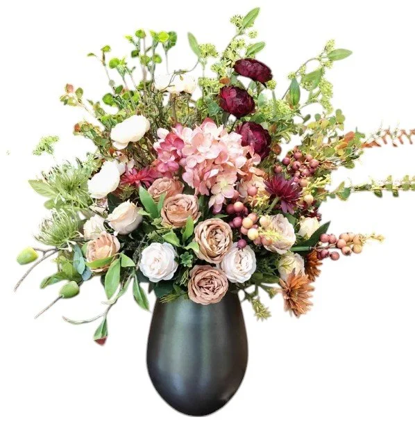 A floral arrangement with pink, white, and burgundy flowers in a black vase.