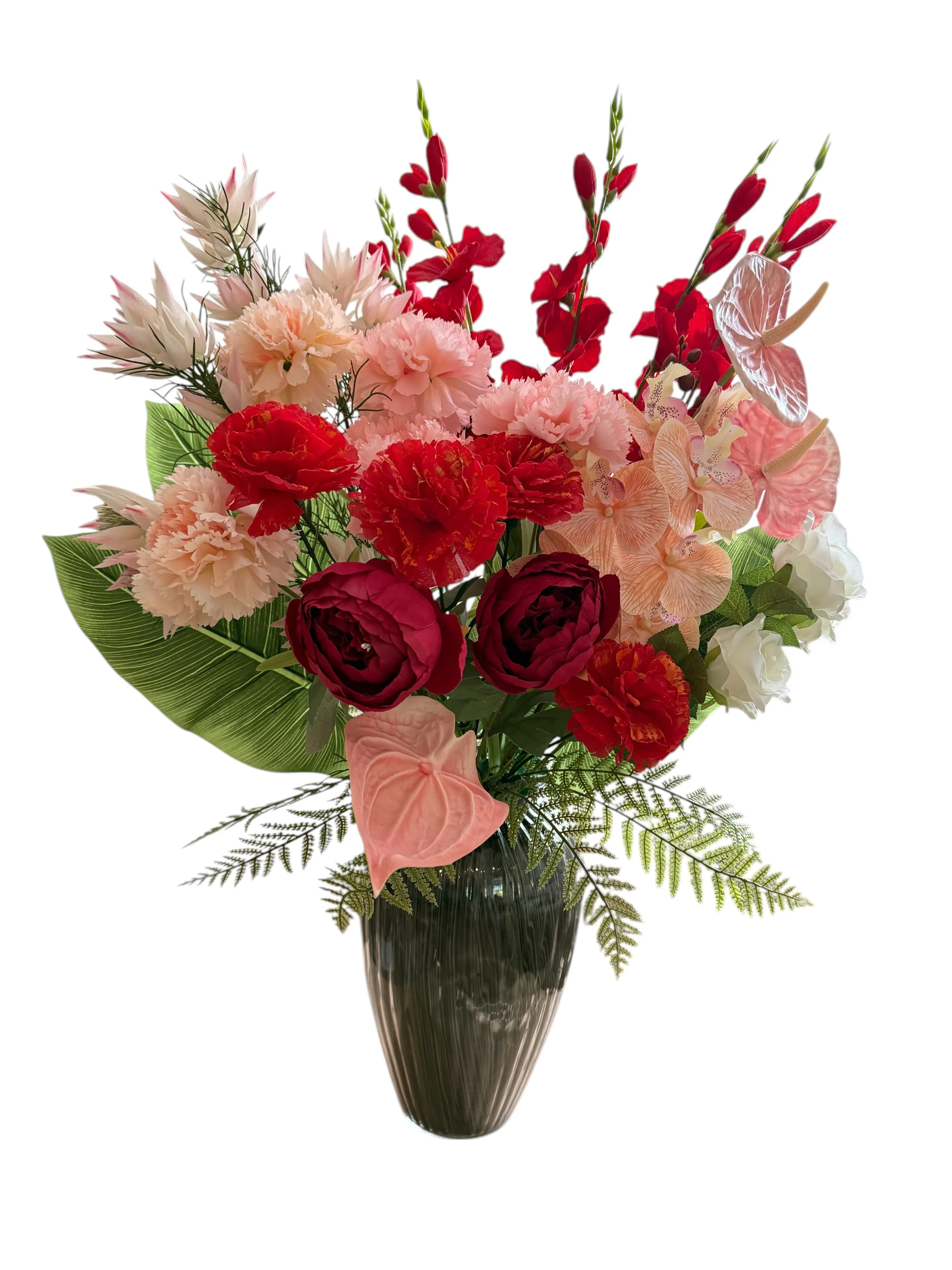 Colorful bouquet of various pink, red, and white flowers in a dark vase.