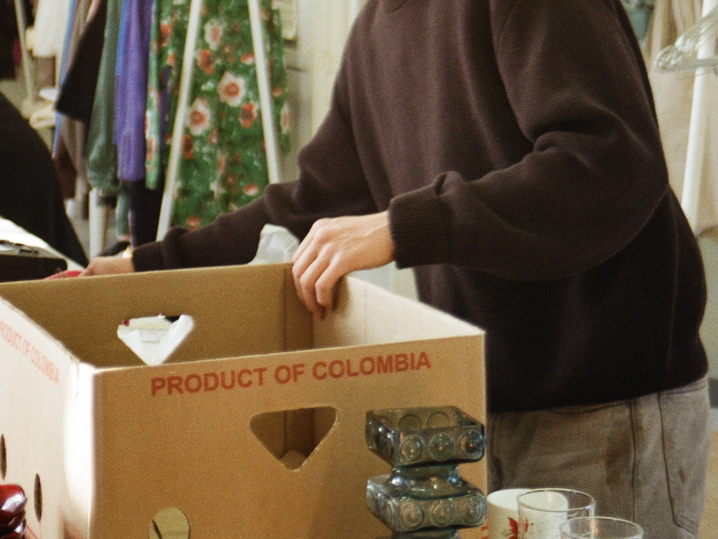 Henkilö pakkaa elintarvikekuplaan, jonka kyljessä lukee 'Product of Colombia'.