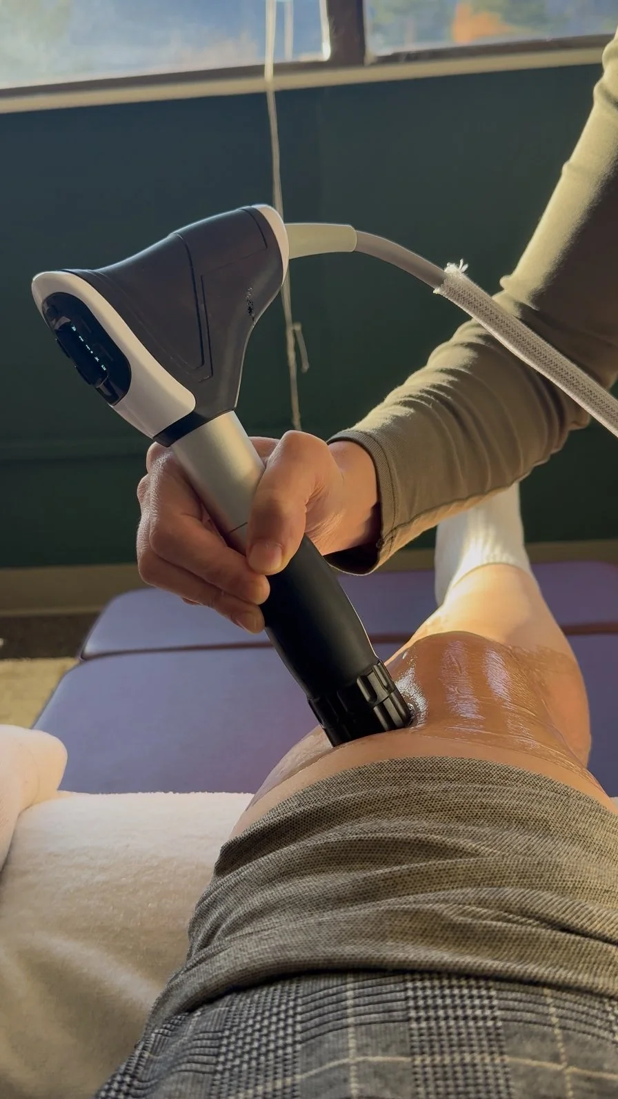 Dr. Leslie using shockwave therapy on a patient’s knee at Destination Chiropractic in Boulder, Colorado
