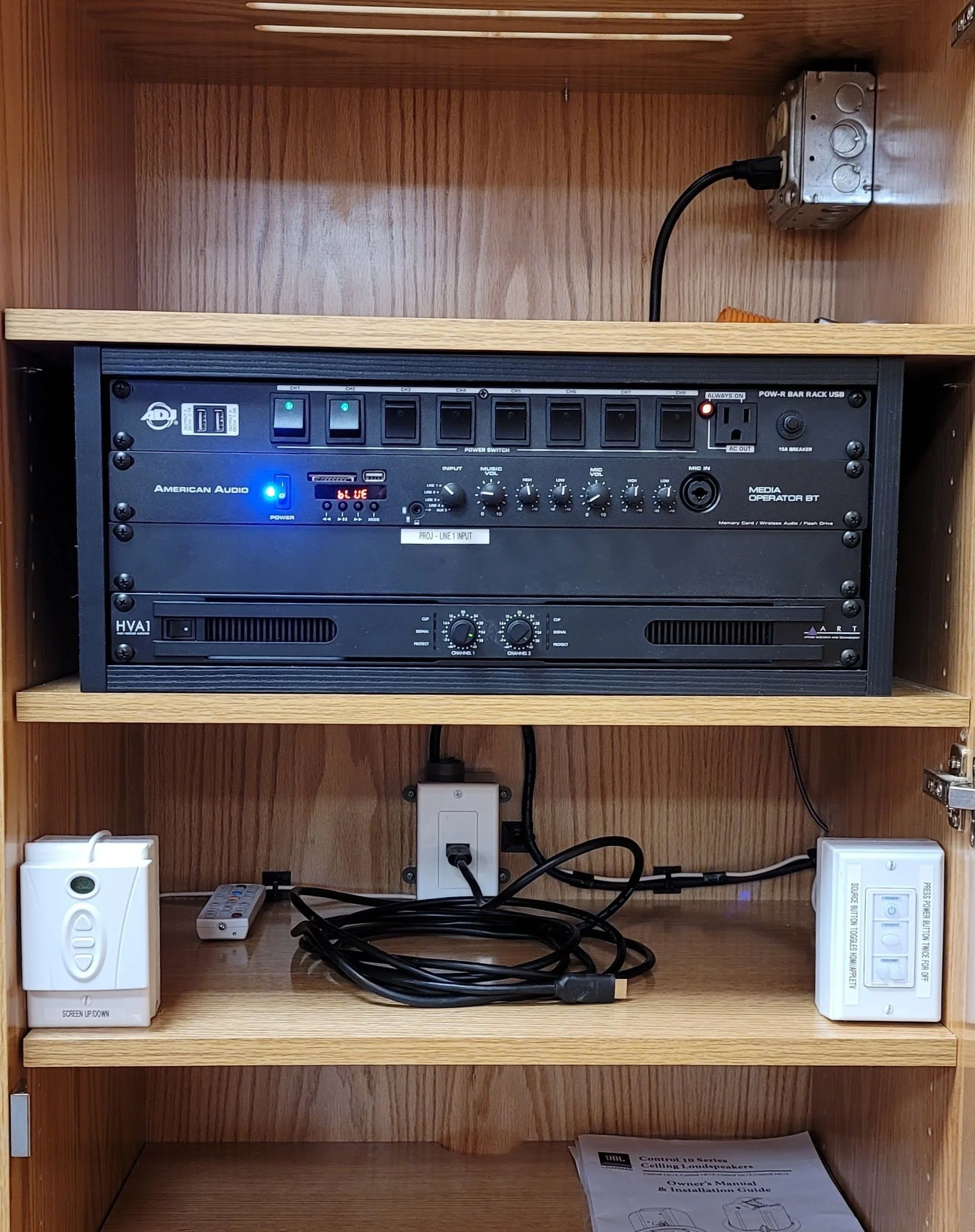 A wooden cabinet with music and audio equipment, including a power rack with switches and meters, and various wires connected to plug outlets.