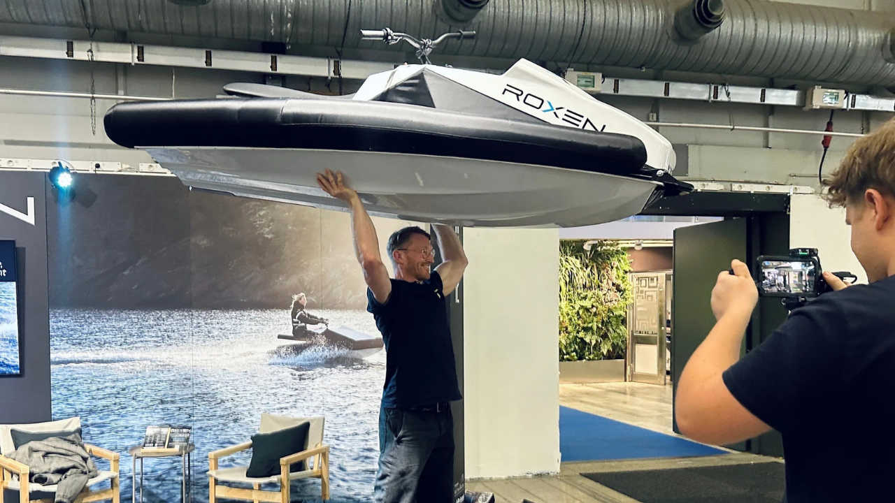 Hombre levantando moto de agua eléctrica Roxen blanca para mostrar su ligereza en una feria tecnológica.