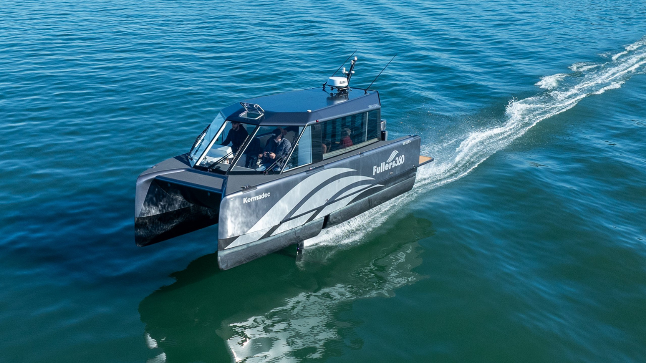 El hidroala eléctrico plateado Vessev VS-9 planea sobre aguas azules con sus foils para transporte marítimo limpio.