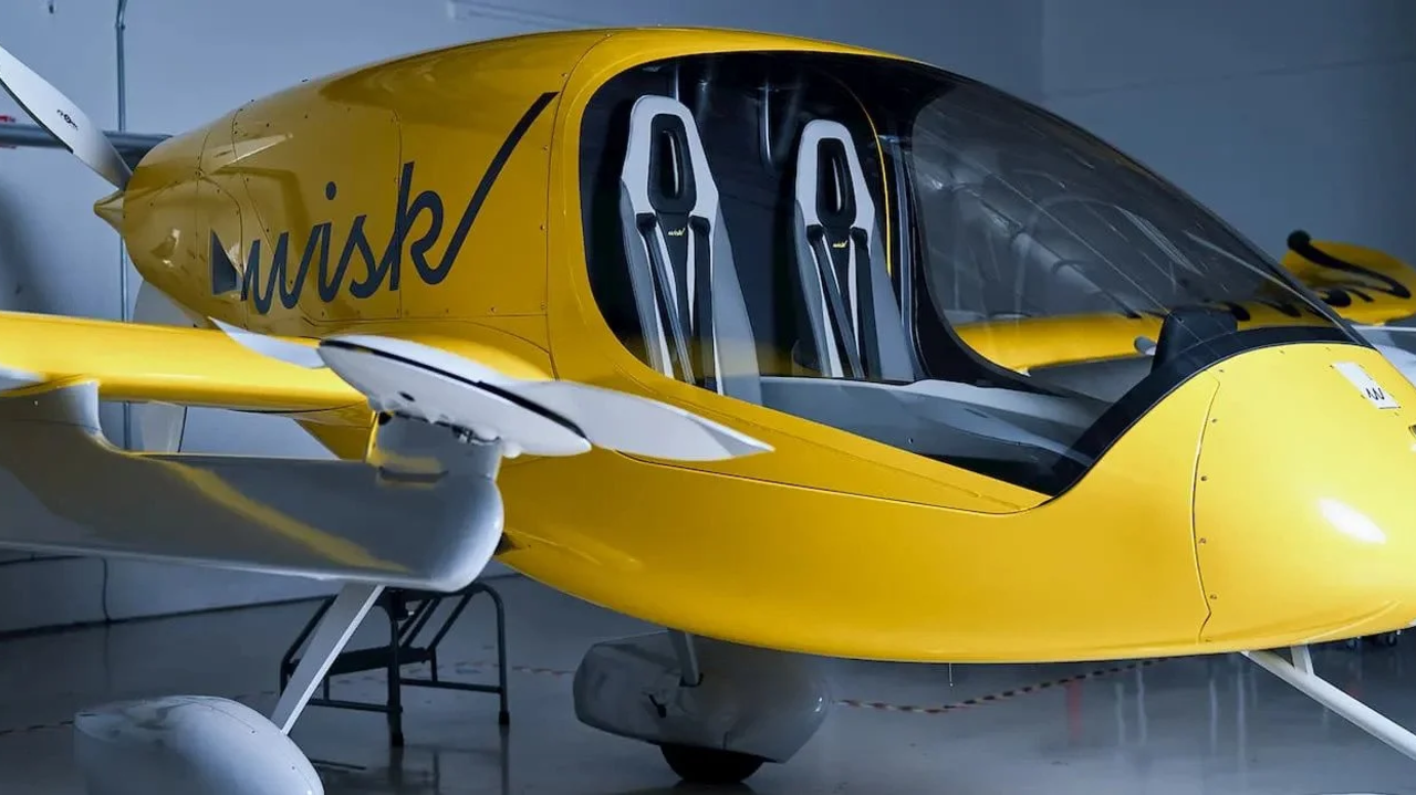 Taxi aéreo Wisk Aero amarillo y blanco mostrando la cabina de dos asientos en un hangar para vuelo autónomo.