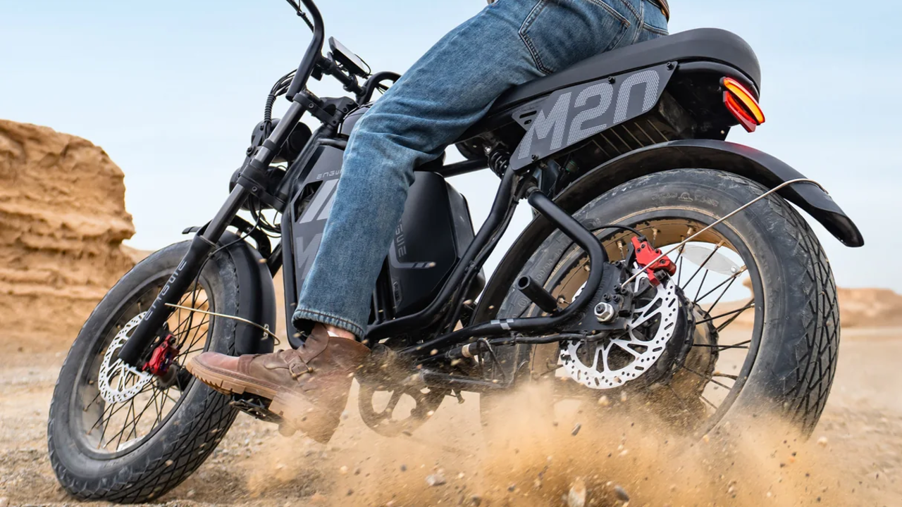 Ángulo bajo de la rueda trasera de una e-bike Engwe M20 negra levantando arena y piedras en un derrape.