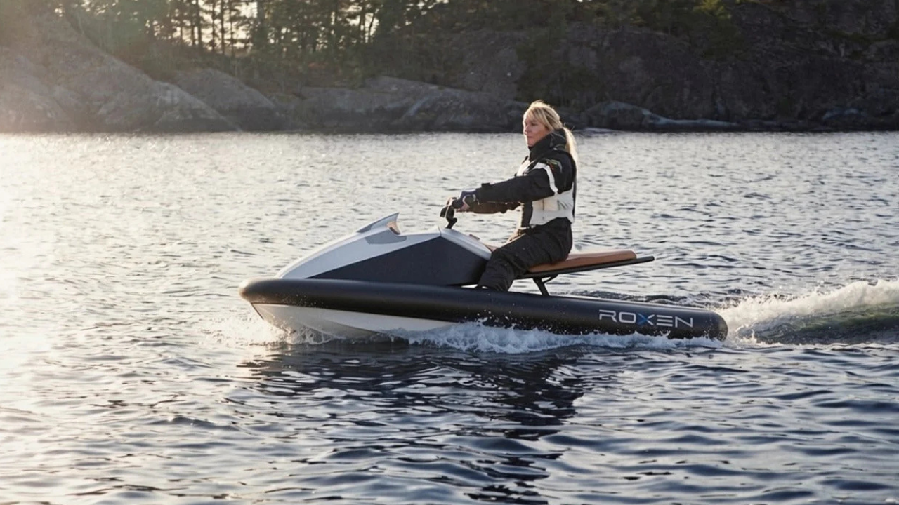 Mujer en moto de agua eléctrica Roxen blanca y negra navegando un lago, destacando la movilidad náutica sostenible.